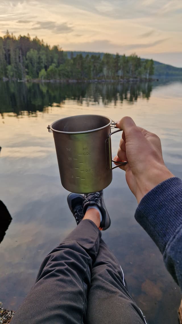 Cup being held with a lake in the background.