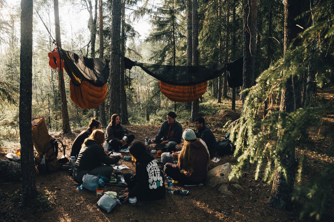 People sitting, cooking, and eating dinner surrounded by hammocks. People sitting, cooking, and eating dinner surrounded by hammocks.
