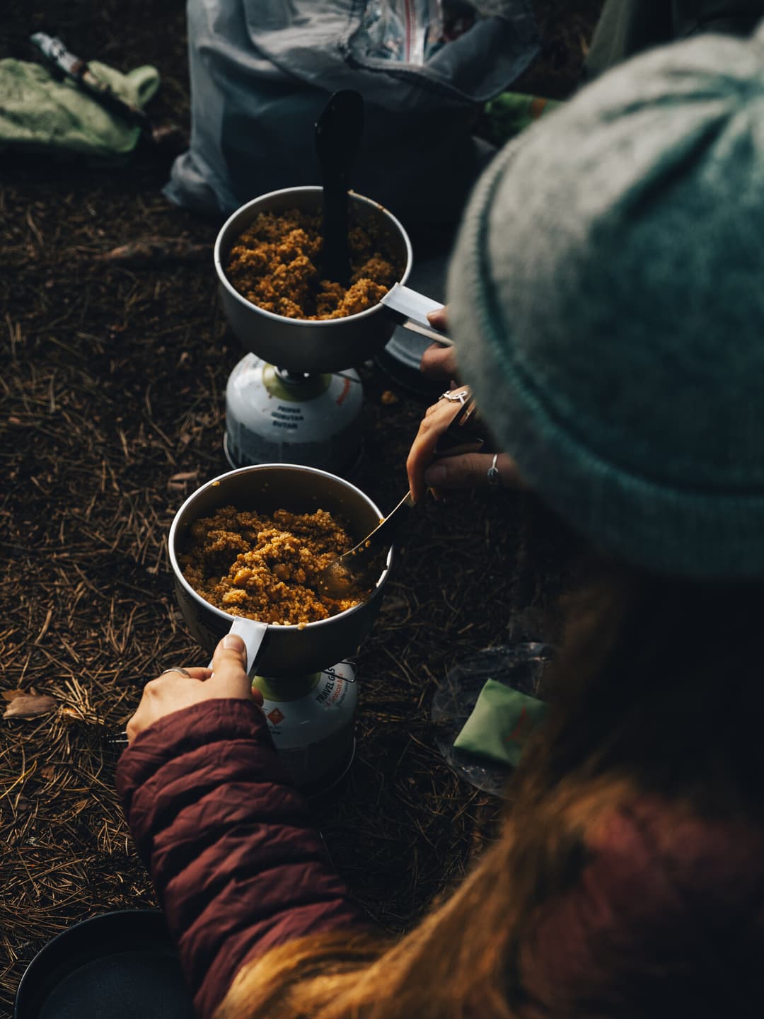 Person cooking couscous on a camping stove. Person cooking couscous on a camping stove.