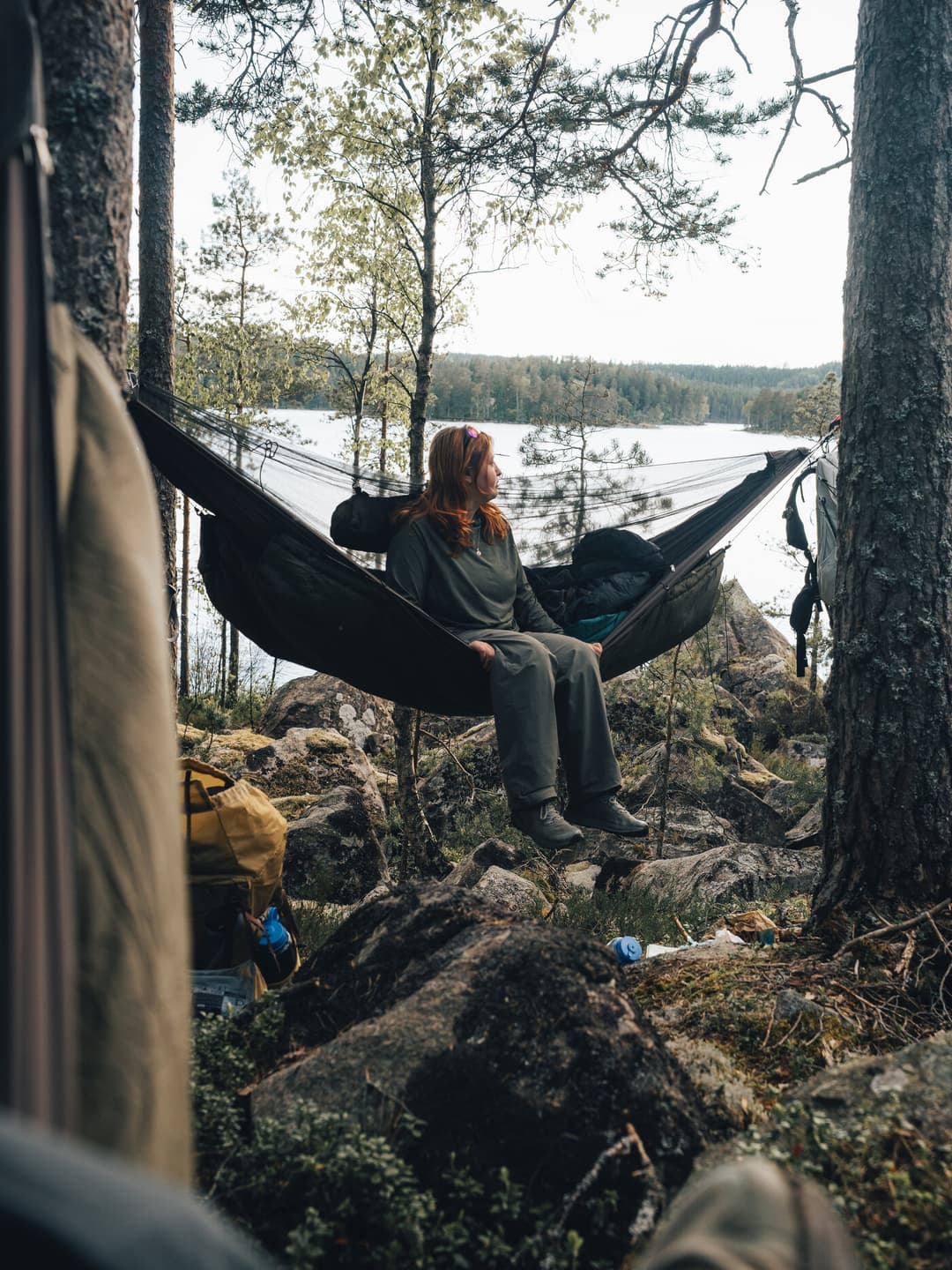 Person sitting in a hammock with a lake in the background. Person sitting in a hammock with a lake in the background.